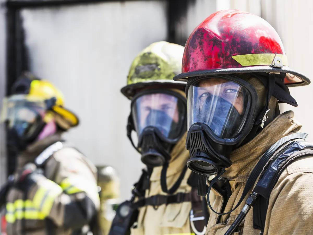 Three firefighters in breathing apparatus and helmets.