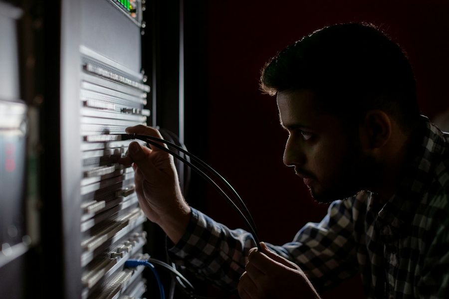 A technician connecting cables in a server rack.